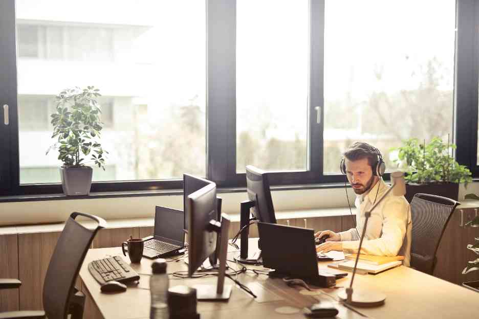 Customer support agent working with multiple monitors and headset in modern office