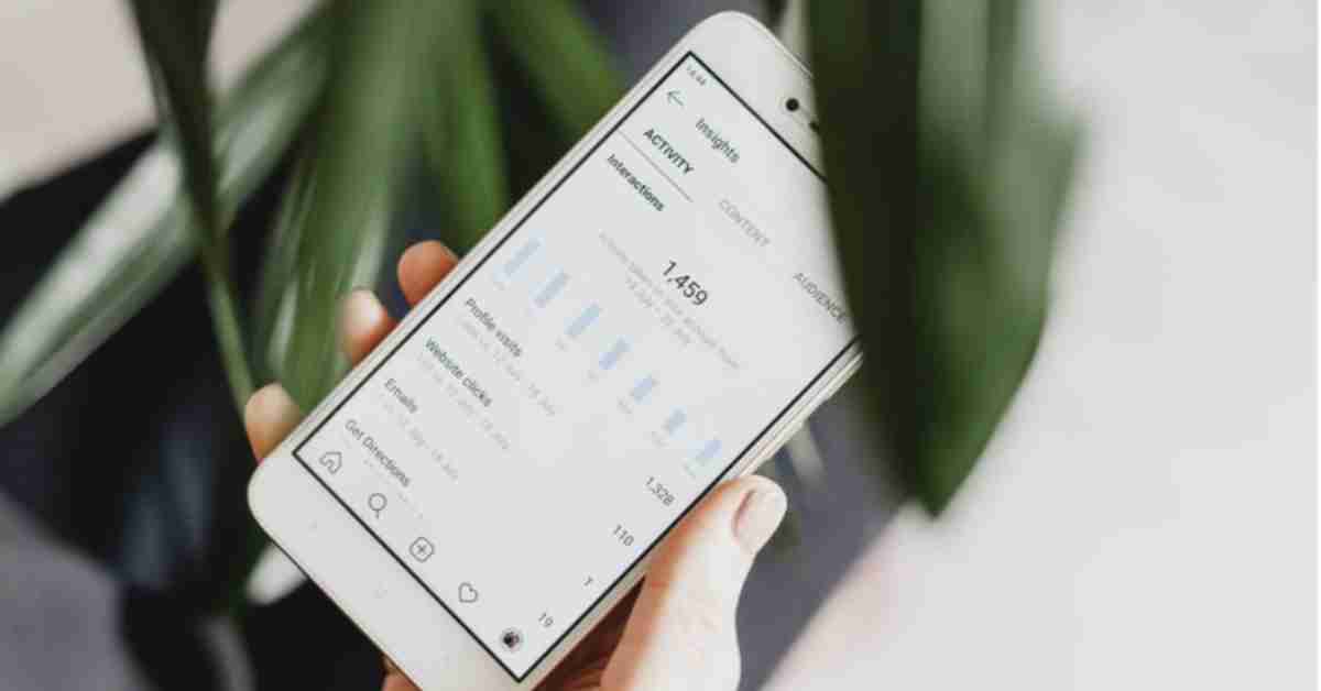 Hand holding a phone showing Instagram analytics dashboard for profile performance analysis.