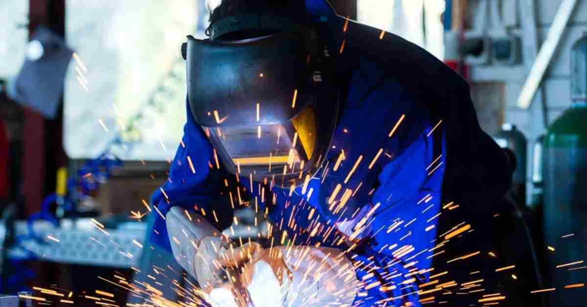 Automated laser welding machine joining metal components with high precision and blue laser sparks.